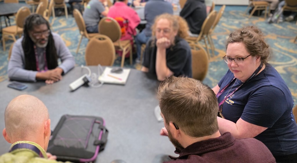 Attendees sit together around a round table at PyCon US 2026, leaning in during a focused small-group conversation about generative AI and open source.
